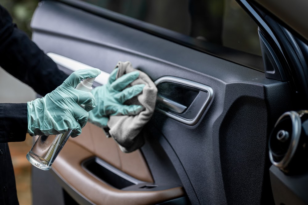 person wearing gloves wiping down inside of car door