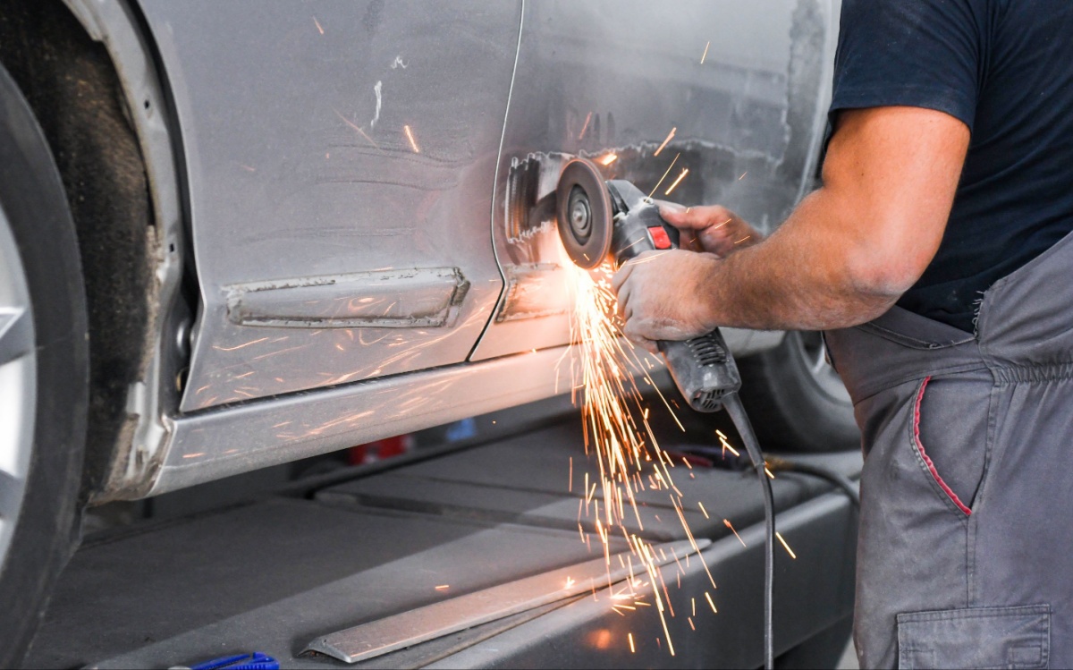 A man cutting through the door panel of a damaged vehicle